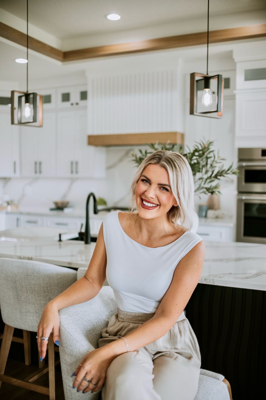 Senada Agic seated at a marble kitchen island in a bright, modern Des Moines home